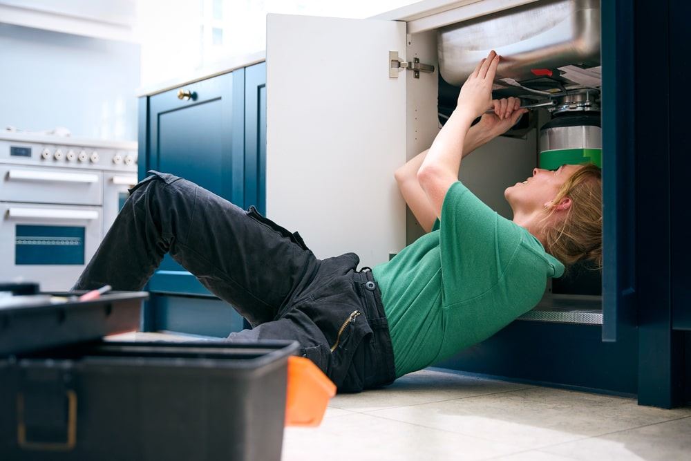 Female plumber fixing garbage disposal unit